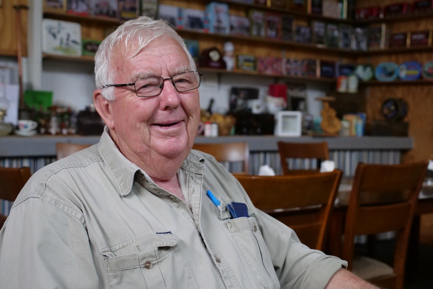 John Hallam sits in his cafe, with lots of knick knacks in the background.