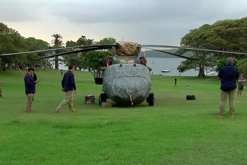 A Black Hawk helicopter sits in the middle of a Sydney park as investigators inspect the aircraft