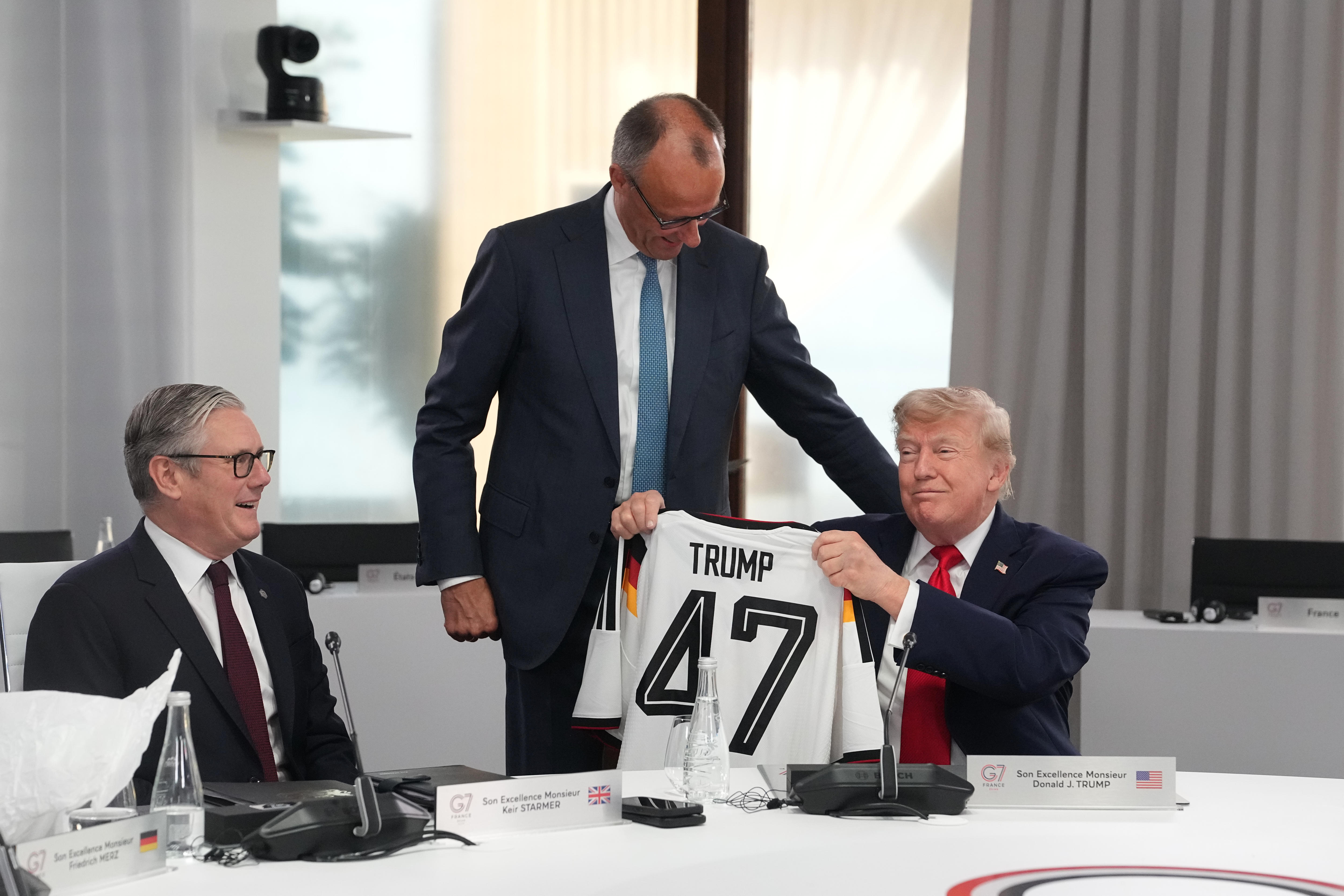 Donald Trump, right, holds up a jersey with the number 47 on it, next to freidrich merz
