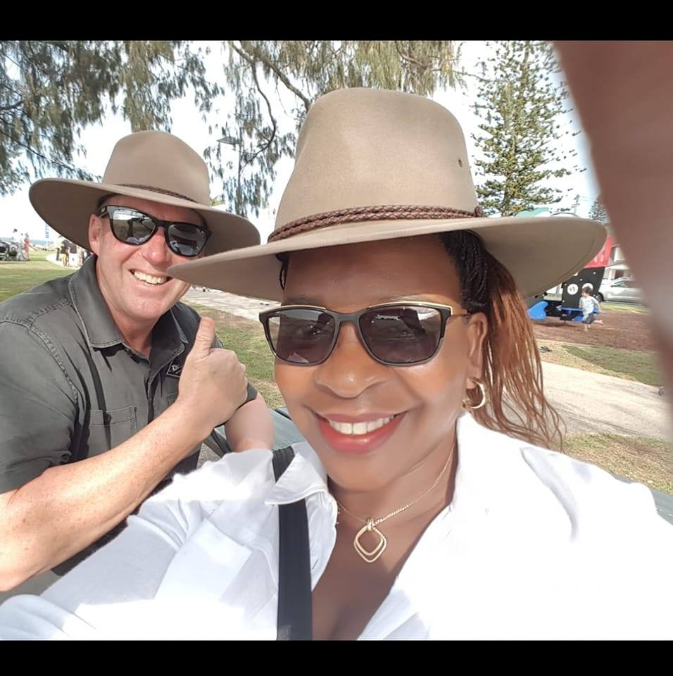 A woman and man in hats and sunglasses smiling