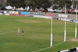 Two players stand in an enlarged goal square during a VFL game.