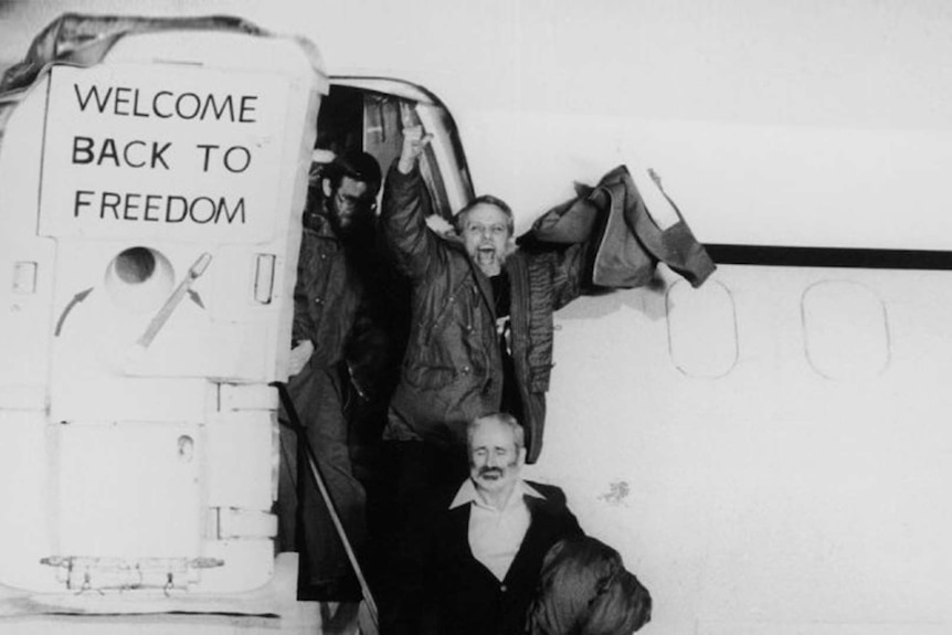 An old photo of smiling men disembarking from a plane