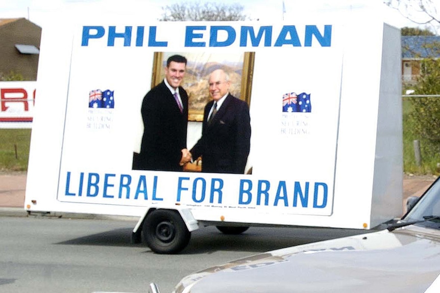 Two men pictured shaking hands in a billboard attached to a panel van