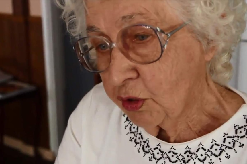 A close-up shot of Mary White, wearing glasses, as she speaks and looks off camera.