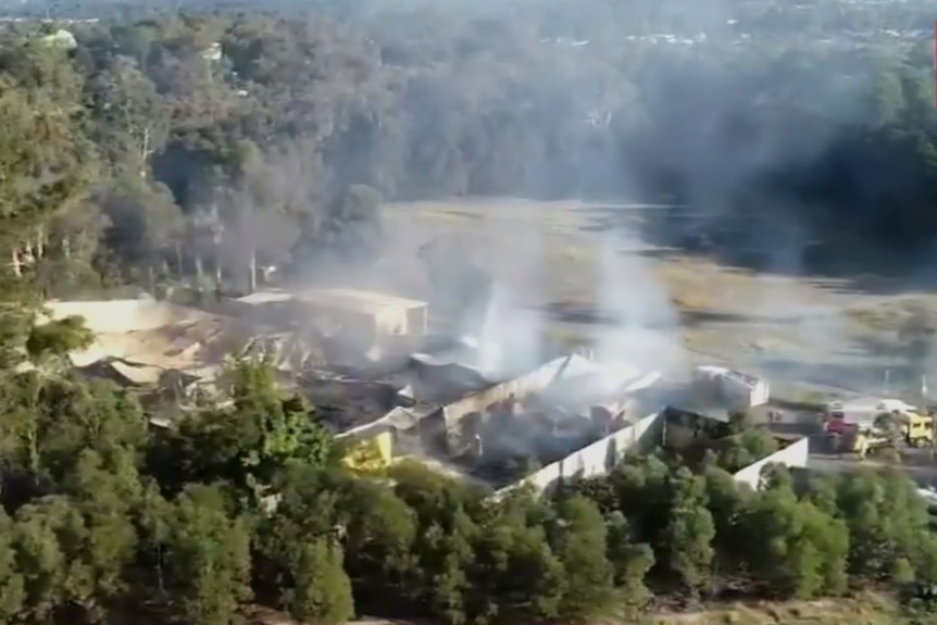 Aerial shot of the burnt-out shell of a building still smouldering