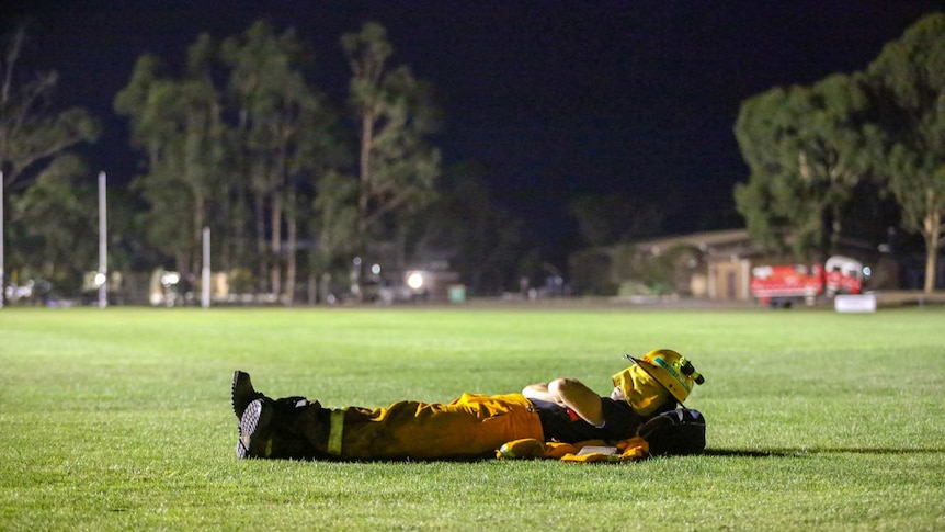 CFA volunteer sleeps on the oval at the Nar Nar Goon staging area