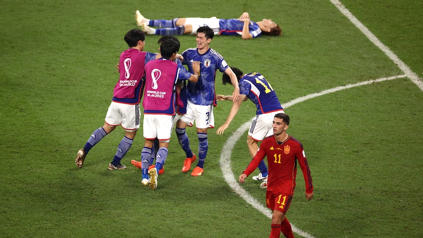 Japanese players celebrate together as Spanish players look disappointed