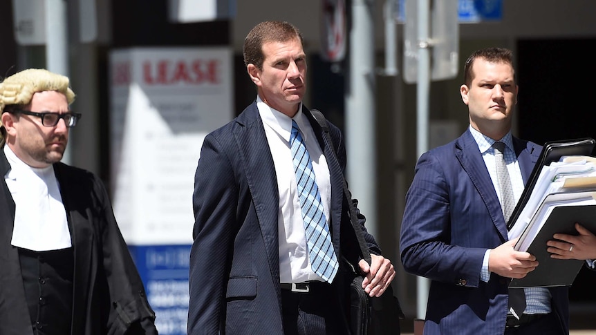 Former Billabong boss Matthew Perrin (centre) arrives for the start of his trial at the District Court in Brisbane