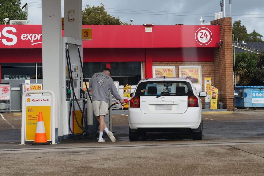 A man filling up his car at a petrol station.