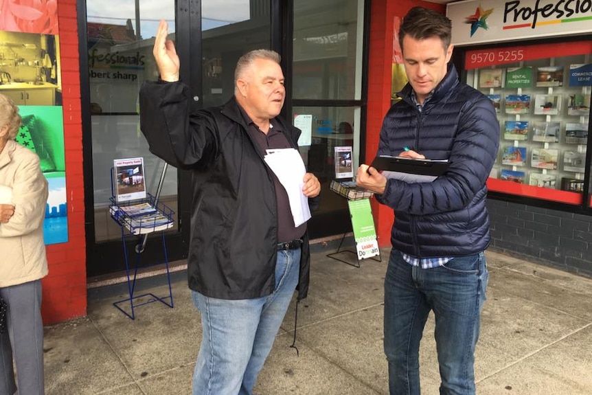 a man speaking to another man and taking notes