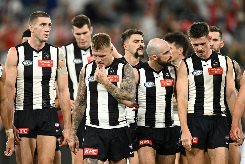 Collingwood AFL players walk from the field after losing to Sydney Swans.