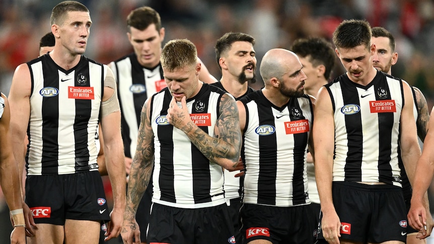 Collingwood AFL players walk from the field after losing to Sydney Swans.