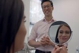 woman looks into mirror with Dr smiling at her