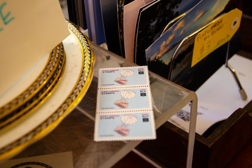 Three stamps are displayed for sale on a table.