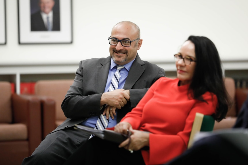 Peter Khalil and Linda Burney, who's out of focus, sit next to each other and look toward the left.