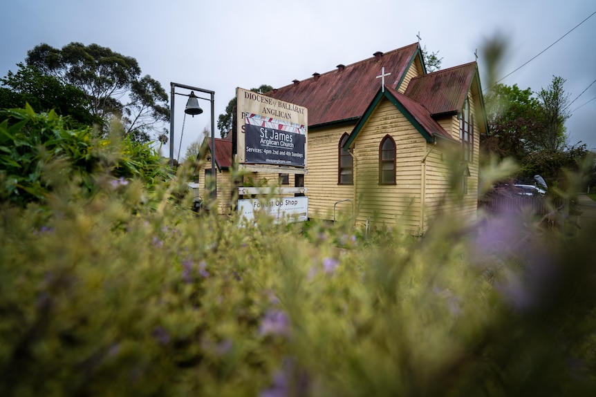 an old weatherboard church with a bell tower next to it. 