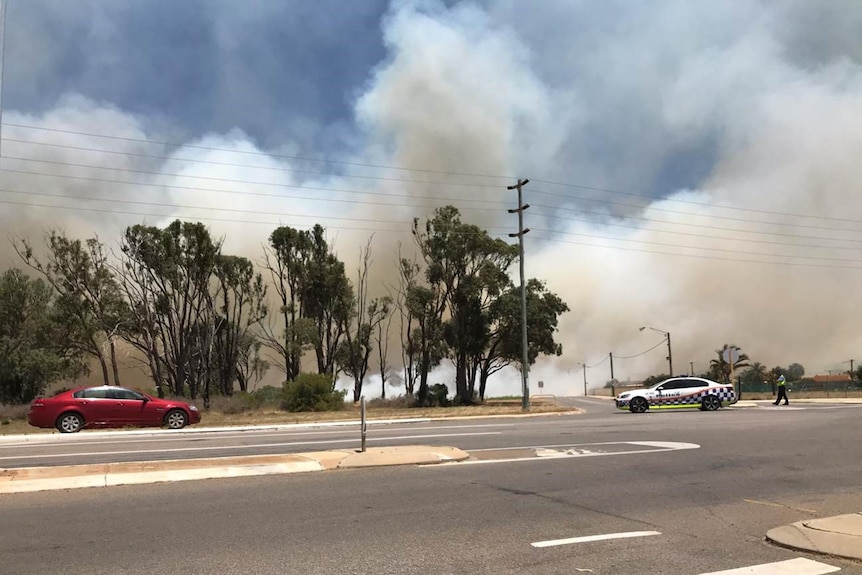 Smoke fills the air with a police car parked in front.