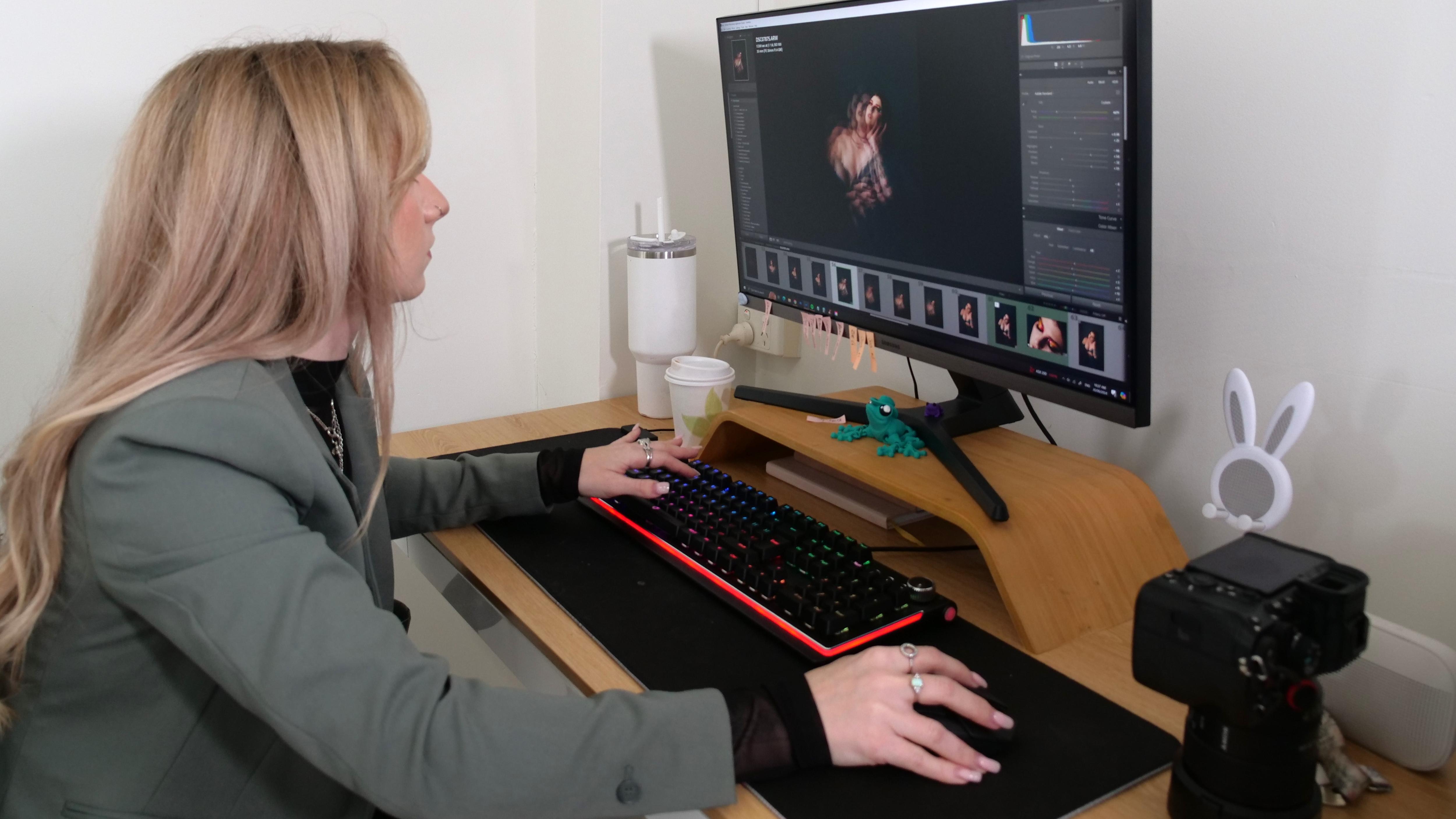 Young woman sitting at a desk in front of her computer editing images. 