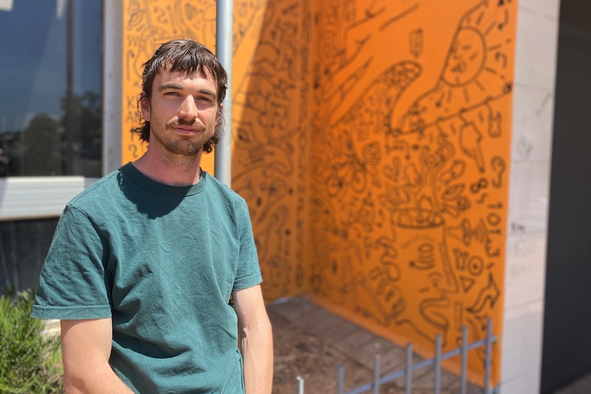 a young man standing in front of orange street art