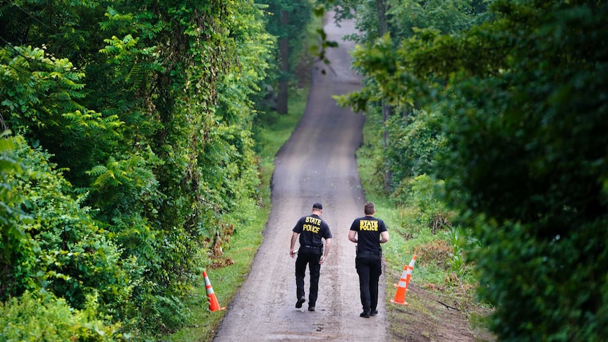 Pennsylvania State Police officers walk up a driveway in Solebury