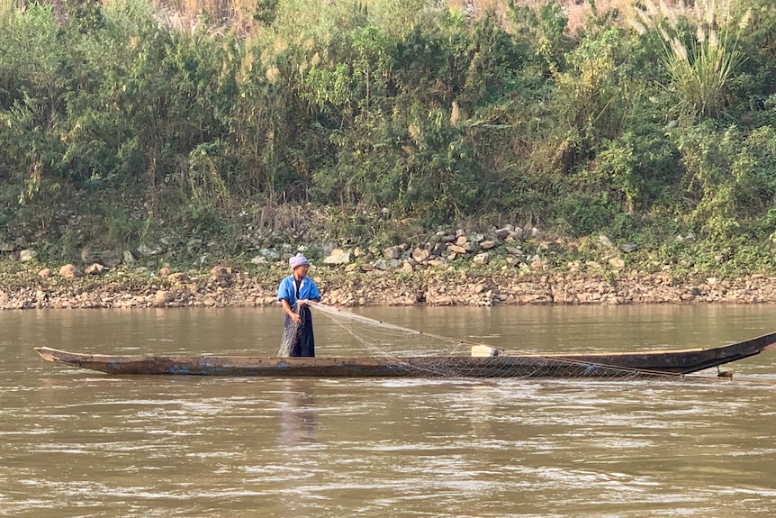 A fisherman throws out his net in the Mekong River.