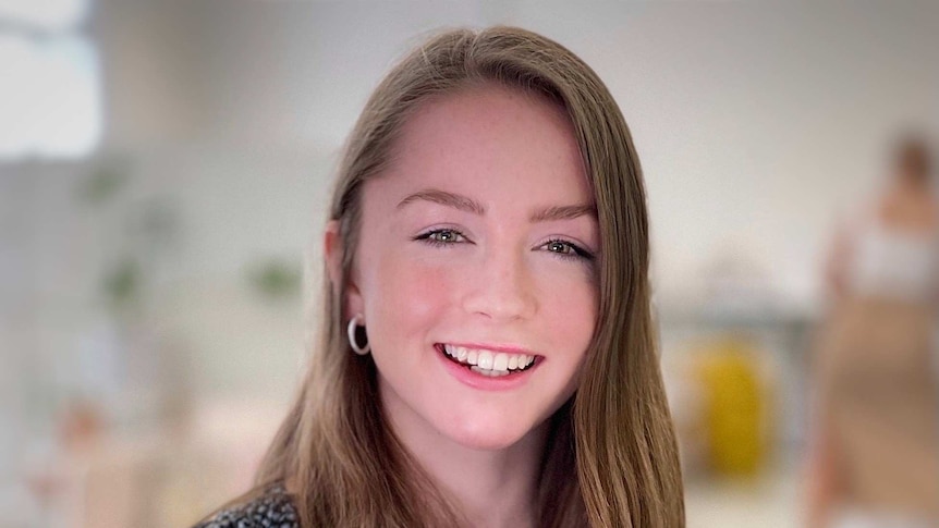 A girl sits and smiles at the camera.