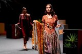 A woman in First Nations fashion walks down a catwalk.