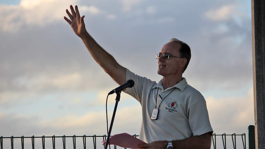 Reverend Stuart Hall raises his hand and voice skywards during prayers for rain in Townsville