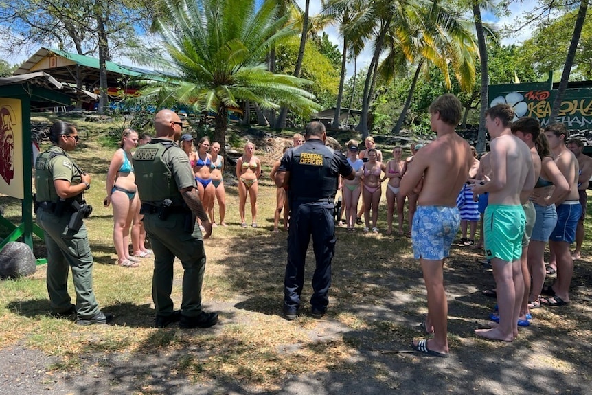 Officers speak to a group of swimmers on a piece of grass Honaunau