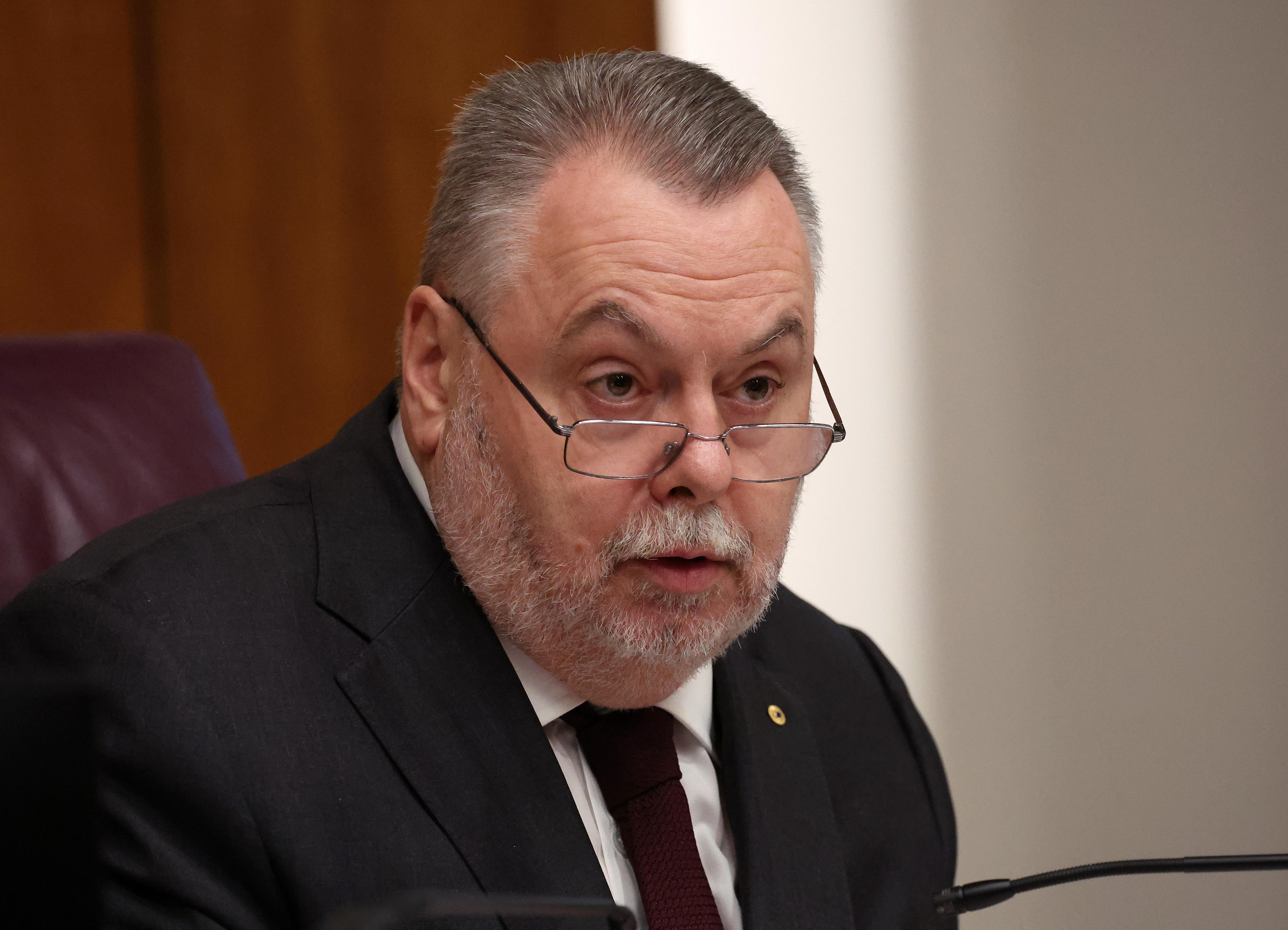Un hombre de traje mirando por encima de sus gafas.