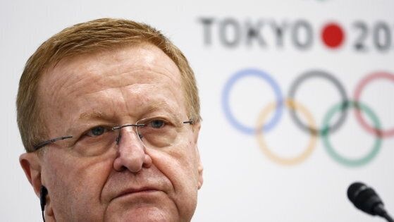 John Coates sits in front of a Tokyo 2020 Olympic logo sign at a media conference.