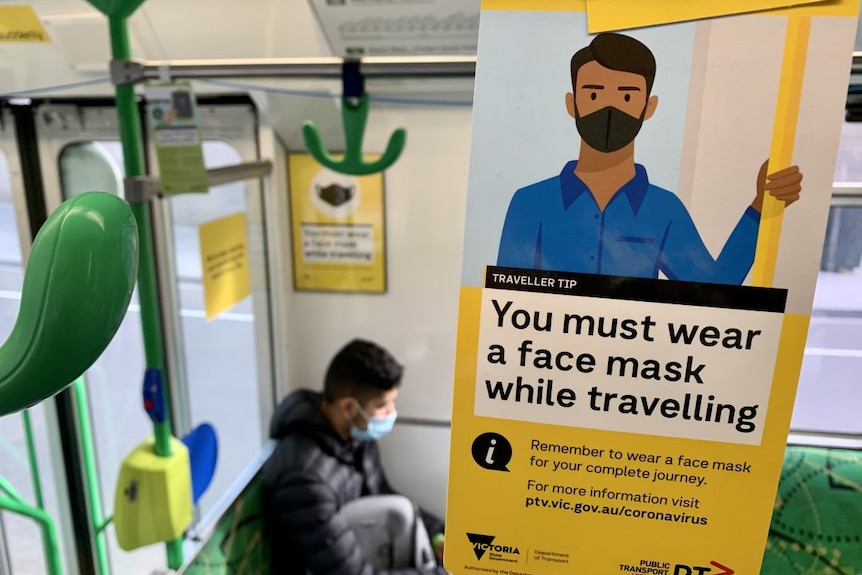 A sign reads 'You must wear a face mask while travelling' on the inside of a tram.