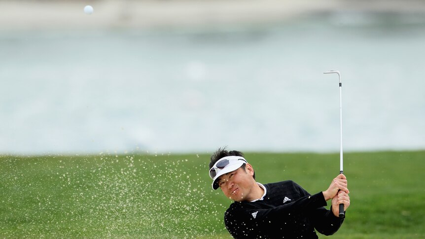 Sand, but not much sun ... Charlie Wi hits out of the bunker in tough conditions at Pebble Beach.