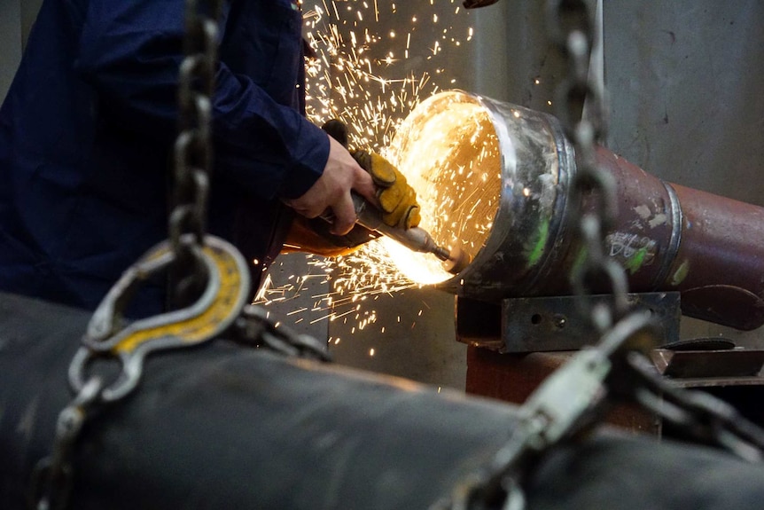 Worker grinds the inside of a pipe at Alltype Engineering, Perth