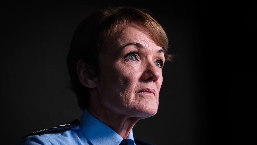 A woman in a blue police shirt stares ahead