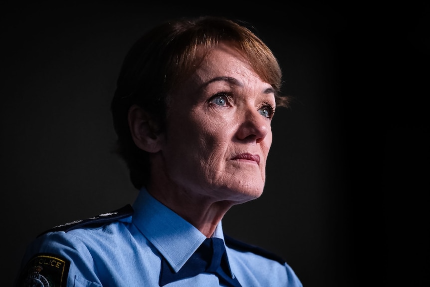 A woman in a blue police shirt stares ahead