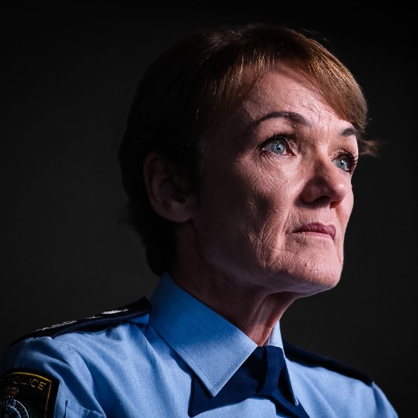 A woman in a blue police shirt stares ahead