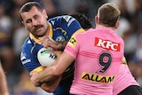 A Parramatta NRL player holds the ball while being tackled by the Panthers.