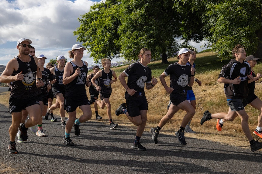 Football team players run along a road.