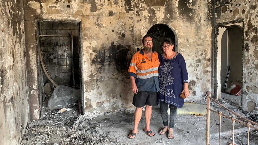Couple standing in  burnt out house