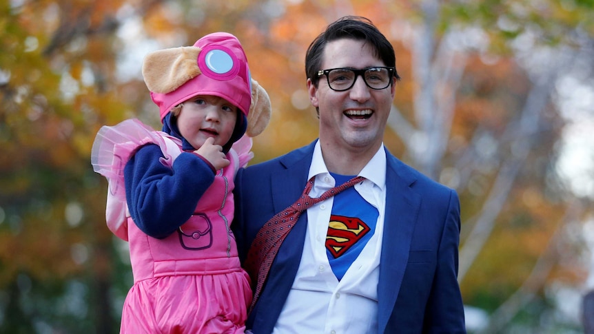 Canada's Prime Minister Justin Trudeau carries his son Hadrien while participating in Halloween festivities