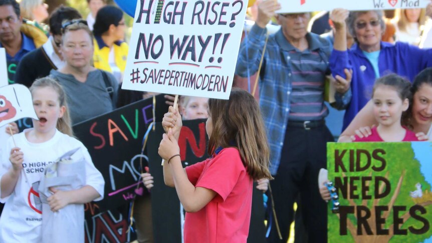 Children and parents hold signs protesting the planned move of Perth Modern School to the city.