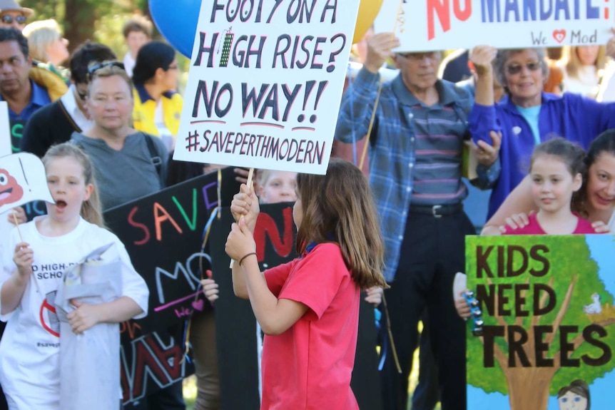 Children and parents hold signs protesting the planned move of Perth Modern School to the city.