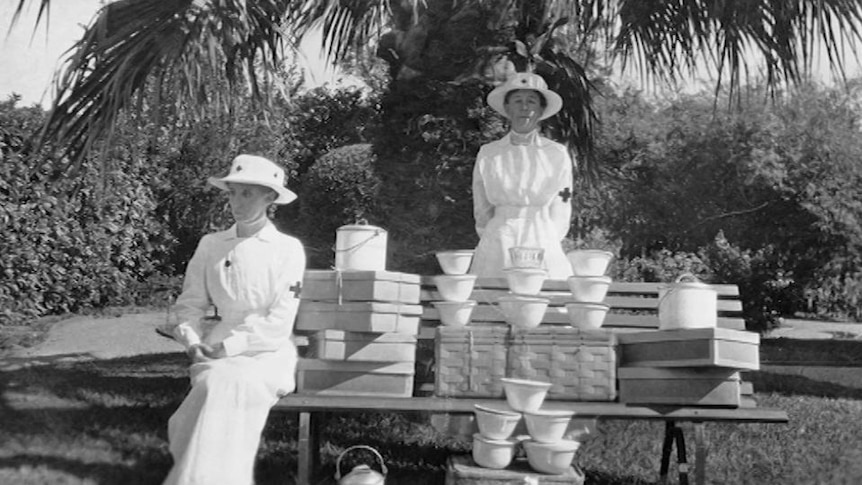 Old photo of two women sit with boxes and containers on park bench