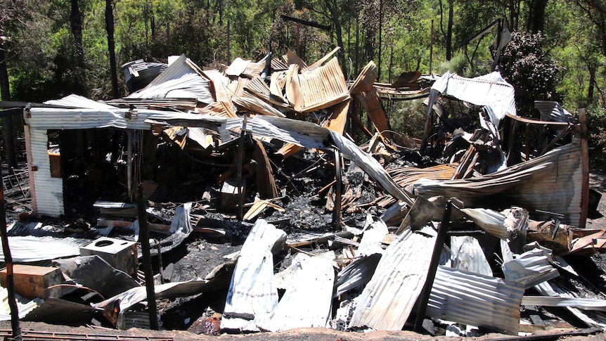 Twisted sheets of corrugated iron are all the remain of a home destroyed by fire in a bush setting.