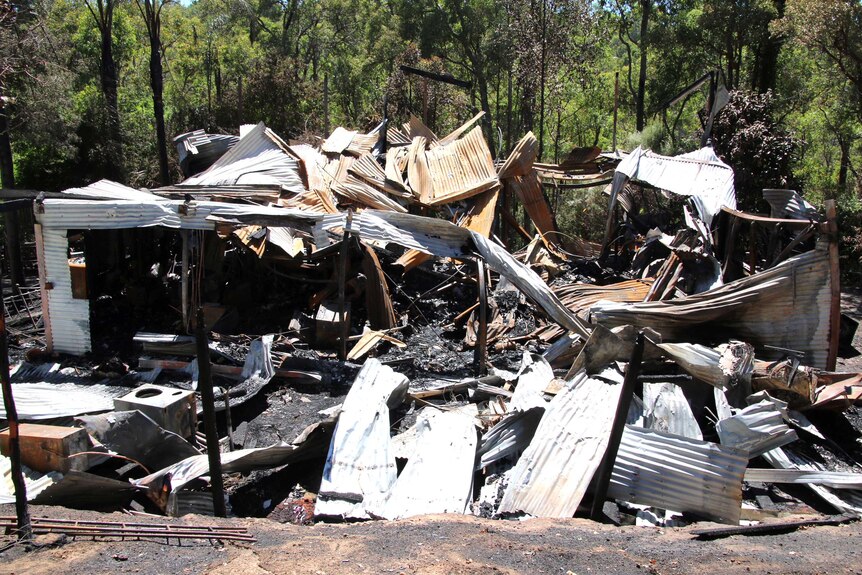 Twisted sheets of corrugated iron are all the remain of a home destroyed by fire in a bush setting.