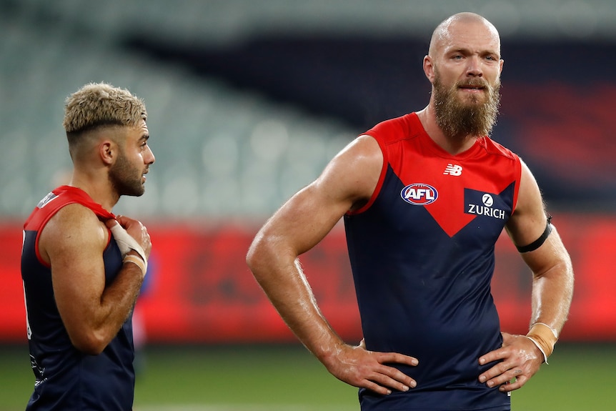 Two Melbourne AFL players look dejected following a loss during the 2020 season.