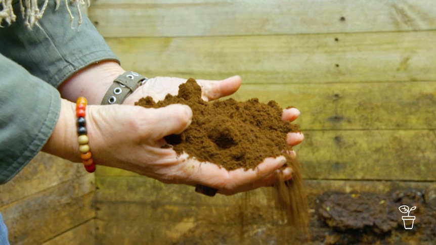 Brown powdery soil-like matter falling through cupped hands