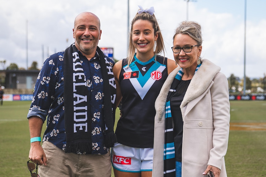 Amelie Borg is pictured with her parents at Alberton Oval in Port Adelaide gear