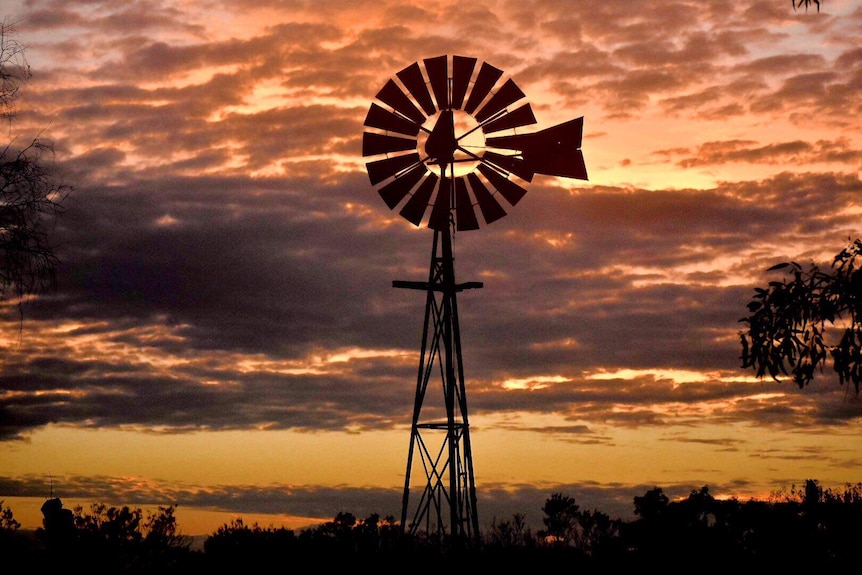 The sun sets on a windmill.